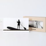 Figura "Paddle surf · Remadora de pie" junto a su estuche y su caja de regalo