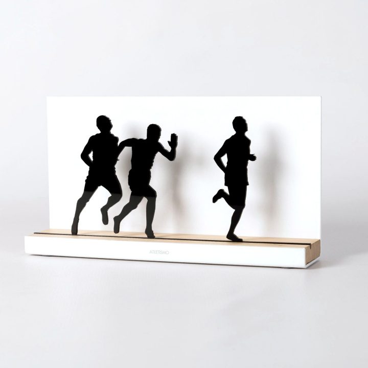 Figura "Atletismo · Tres corredores", vista en perspectiva con su peana de roble