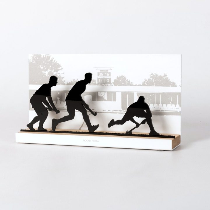 Figure "Hockey sur gazon · Trois joueurs, tacle glissé", vue en perspective avec son socle en chêne