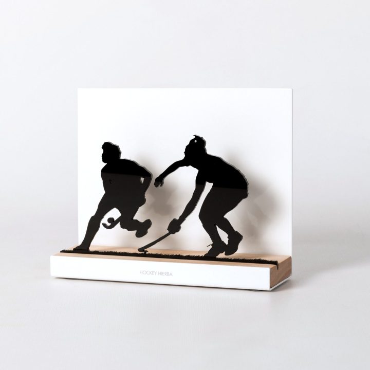 Figure "Hockey sur gazon · Duel de joueuses", vue en perspective avec son socle en chêne