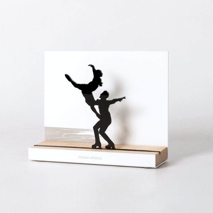 Figura "Patinaje artístico · Pareja en elevación", vista en perspectiva con su peana de roble