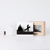 Figure "Snowboard · Board in hand among the pines" next to its sleeve and its gift box