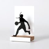 Figure "Basketball · Woman player dribbling", angled view showing its oak base