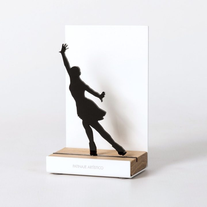 Figura "Patinaje artístico · Ina Bauer con arqueo de espalda", vista en perspectiva con su peana de roble